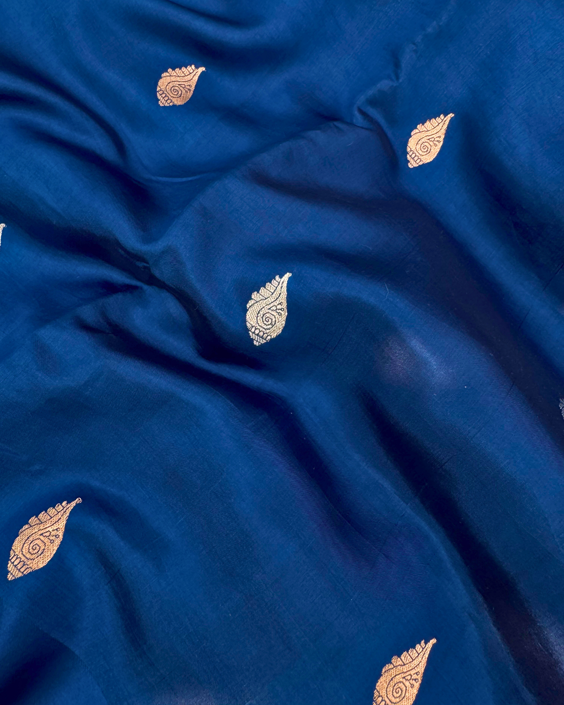 Draped pleats showing rich fluid texture of deep sea blue Banarasi saree