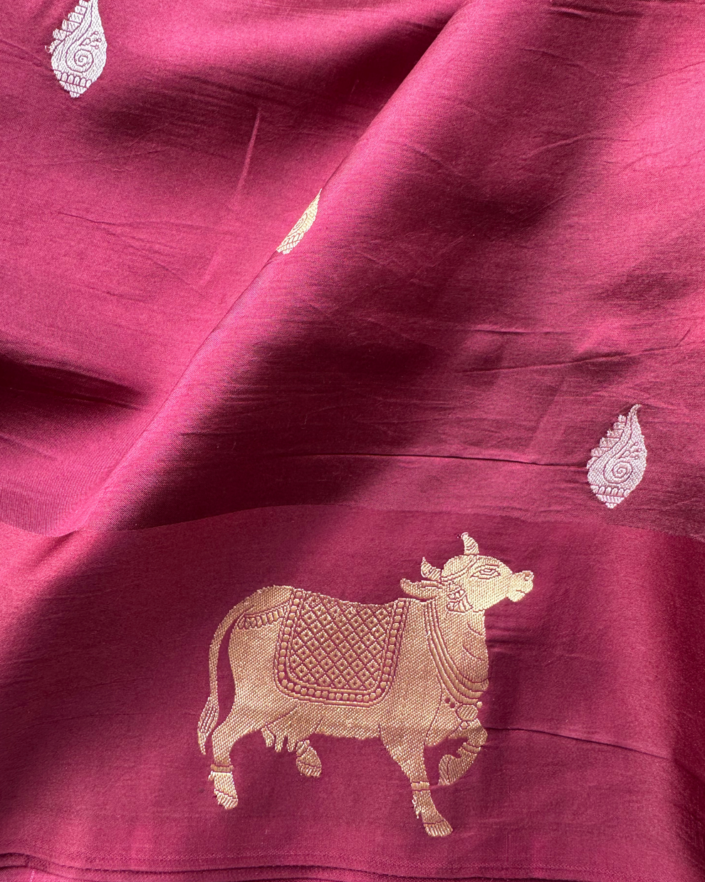Close-up of soft silk texture and cultural motifs on wine Banarasi saree