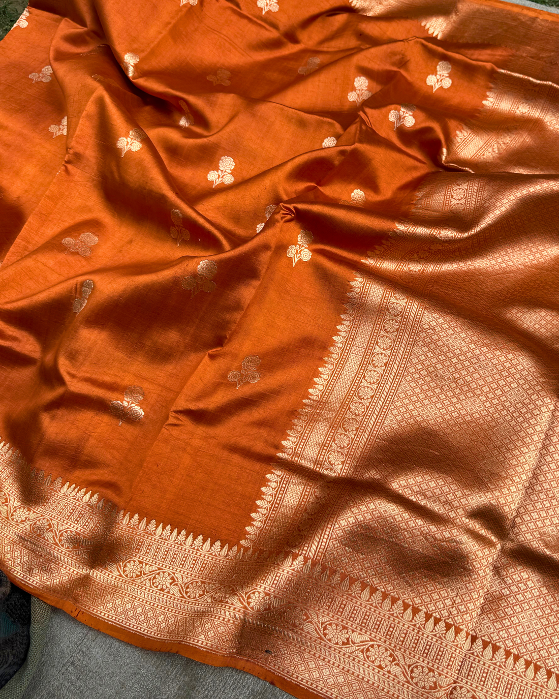 Draped pleats view highlighting soft luster of dusty orange Banarasi saree