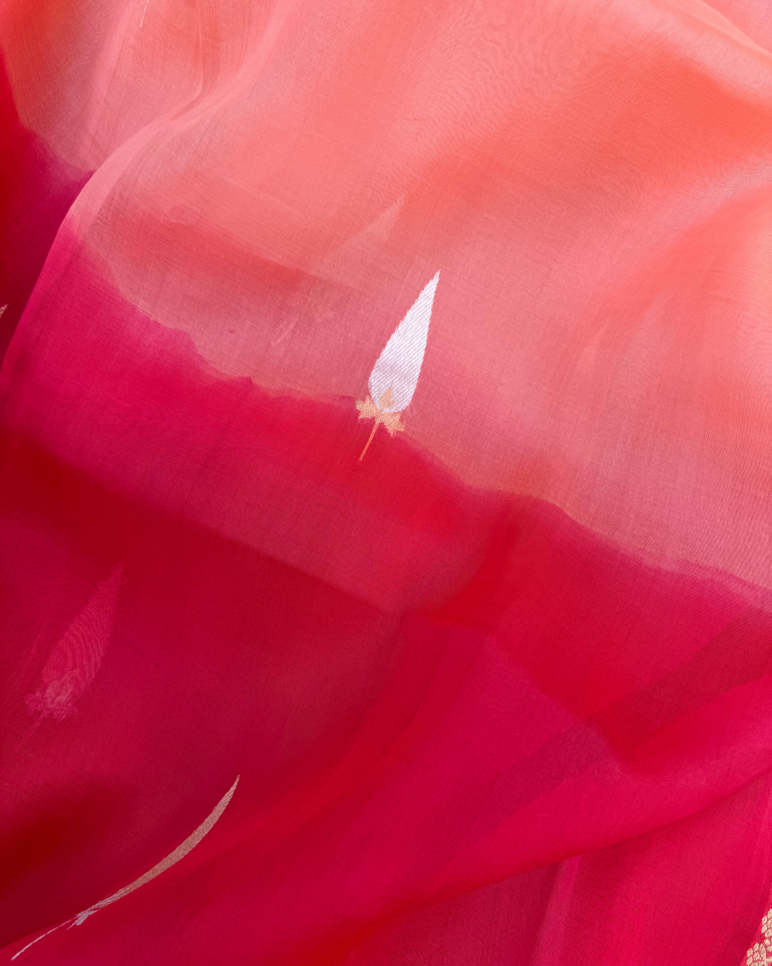 Draped pleats showing sheer handloom texture of red peach Kora silk saree